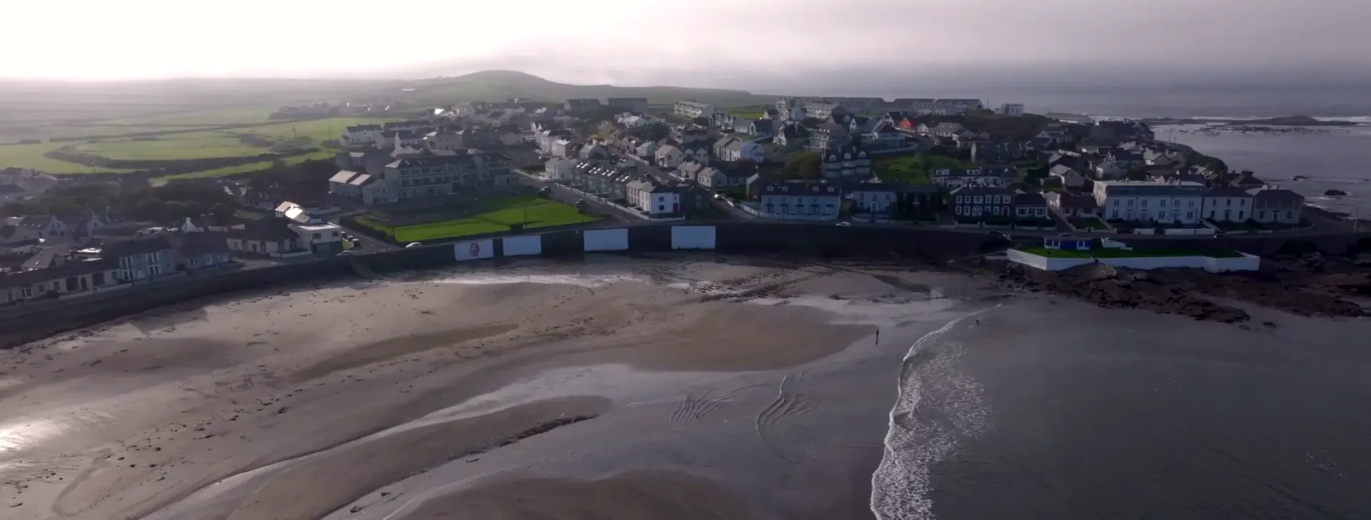 Kilkee beach and sea wall beneath the town on an overcast day