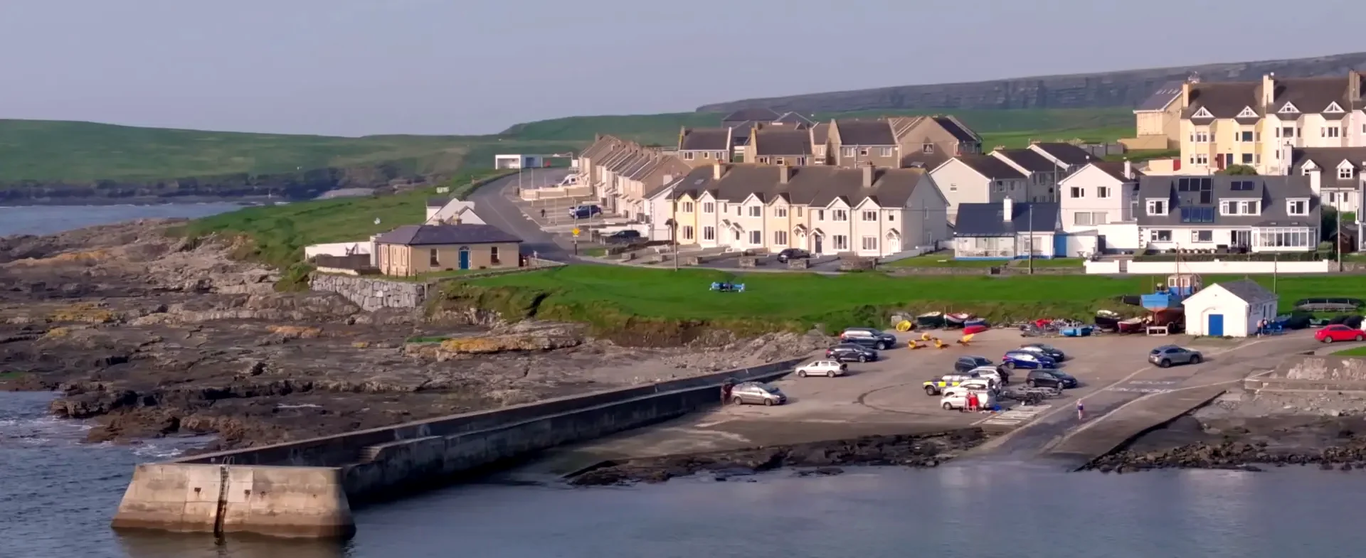 Aerial photograph of Kilkee pier and slipway with boats and coastal houses